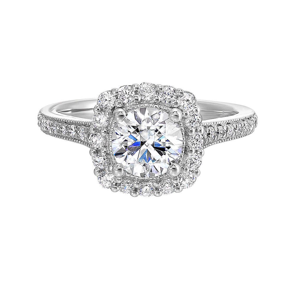 This romantic engagement ring features a round solitare with milgrain details adorned with a delicate cushion style diamond halo and a thin pave band.