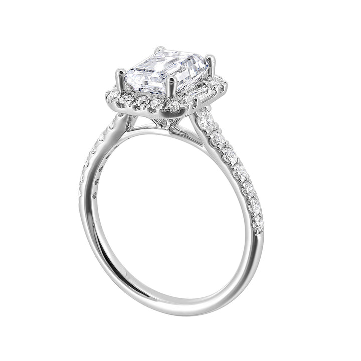 A glittering softened halo of diamonds surrounds the center emerald with adjacent baugettes on both the sides. Pave split shank adds a stylish, dazzling look.